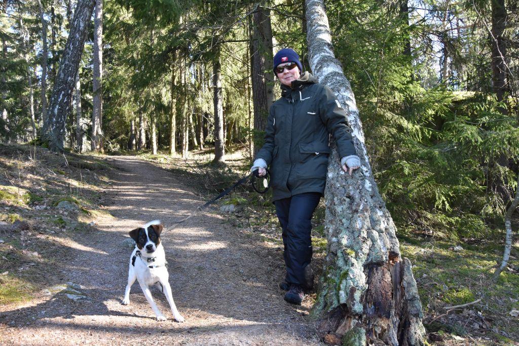 Vit kvinna i skogen tillsammans med liten hund.
