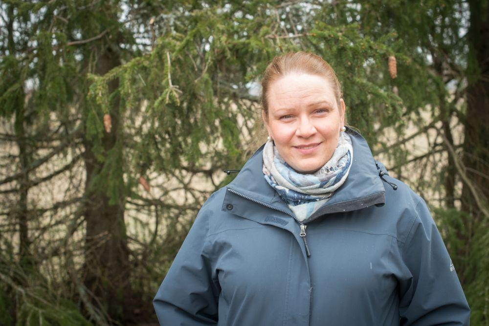 Kvinna med skog i brakgrunden. 