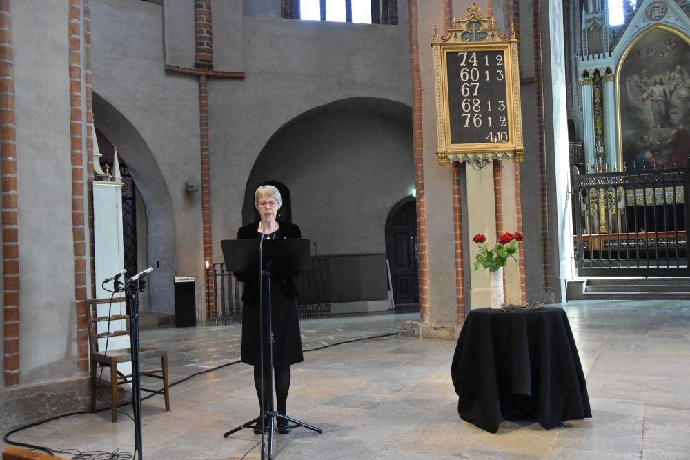 Svartklädd kvinna står framför ett notställ i en kyrka.
