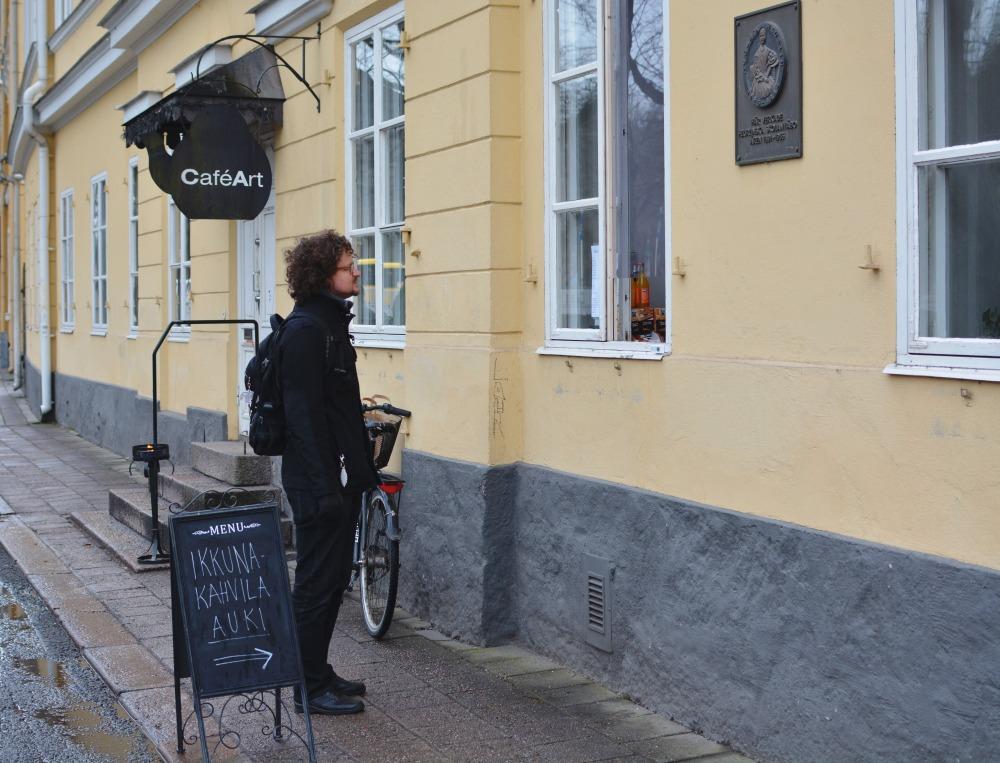 Man står utanför gul byggnads fönster