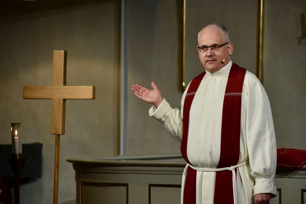 Kyrkoherde vid ett kors i en kyrka. 