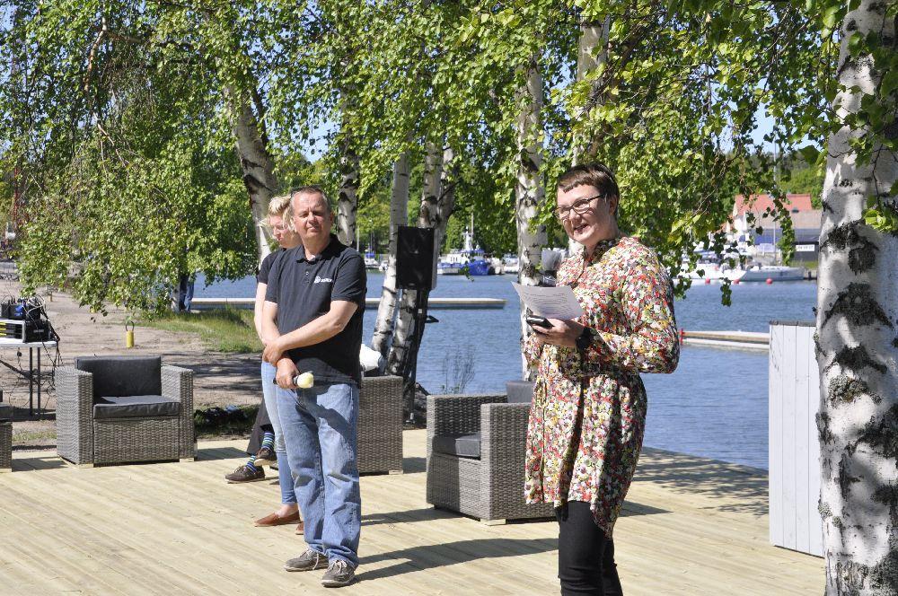 tre persner står på ett trägolv ovanför en hamn