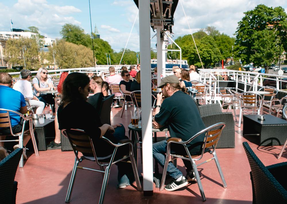 övre däck på restaurangbåt. Hälften av platserna fyllda.