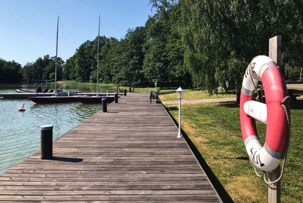 En brygga med en livboj på en ställning intill ett grönt landskap