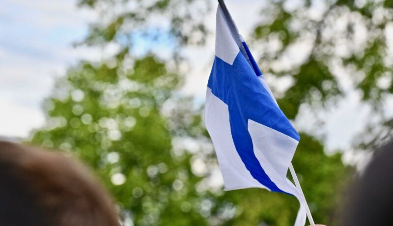 En hand som viftar med en finlandsflagga.