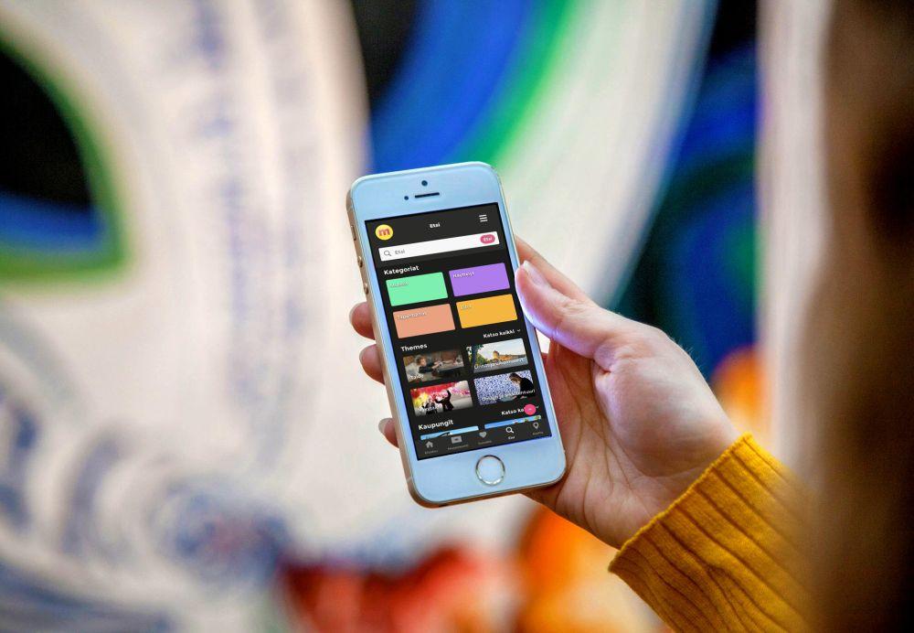 En hand håller i en smarttelefon med en färgglad app öppen på skärmen.