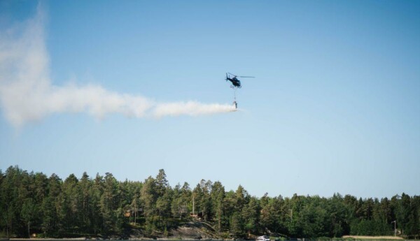 Helikopter släpper ut kalksten ovanför vatten.