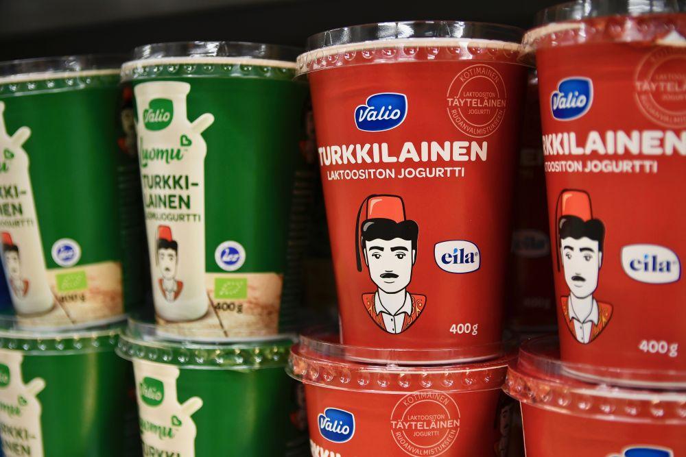Gröna och röda burkar med turkisk yoghurt av märket Valio. Båda förpackningarna är dekorerade med en ritad turkisk man med en fez på sig.