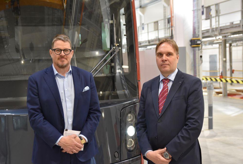 två kostymklädda herrar framför spårvagn
