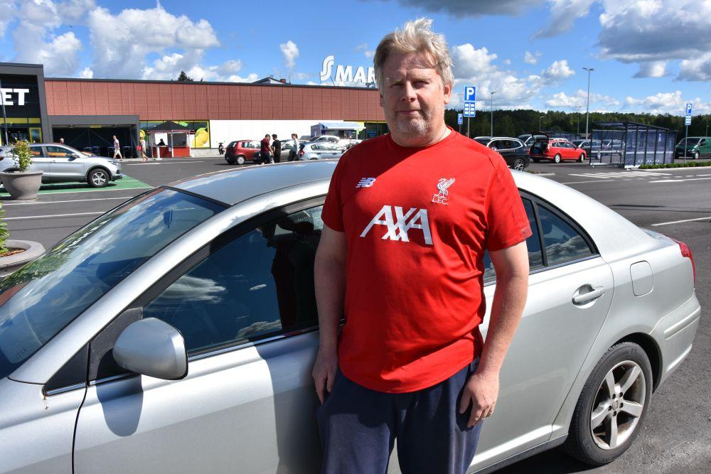 En man står vid sin bil på en parkering.