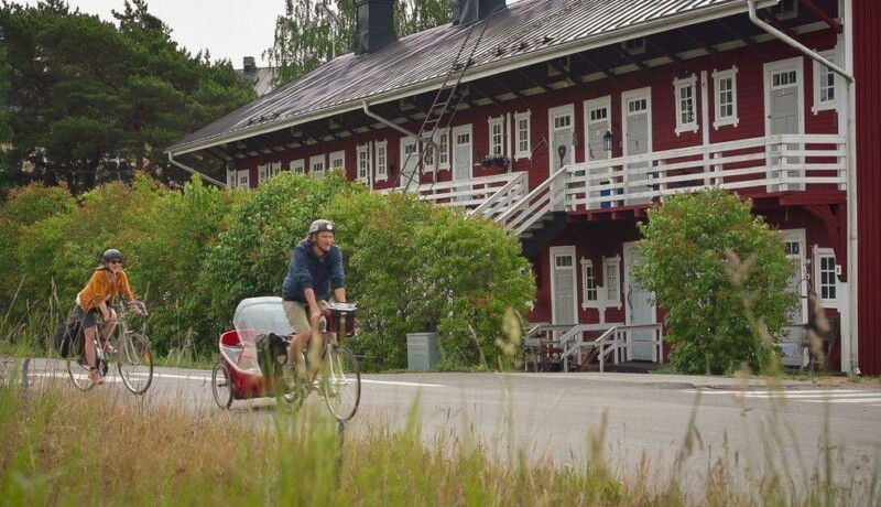 Två cyklister åker förbi ett rött loftgångshus