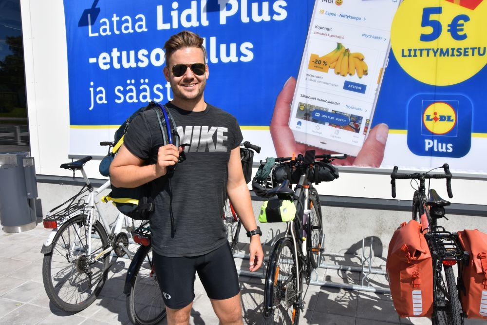 En man står vid cykeln på en parkering.