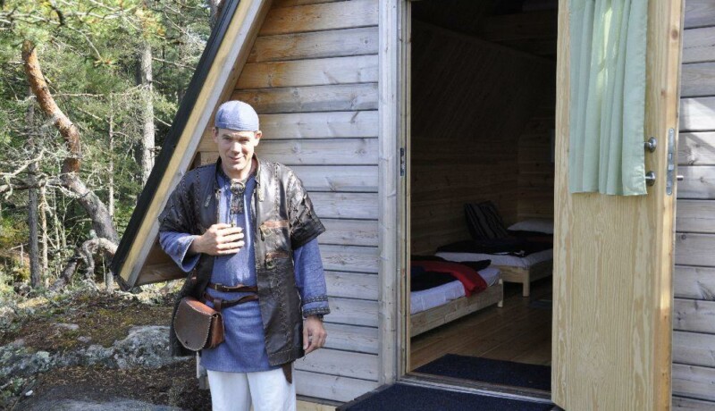 man utanför dörren till en trästuga