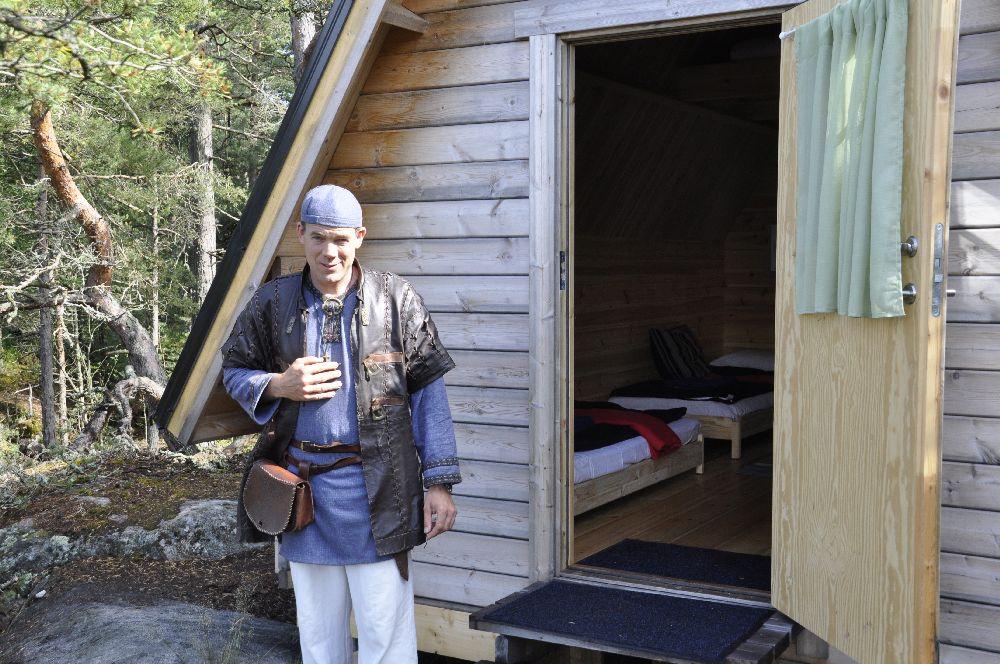 man utanför dörren till en trästuga