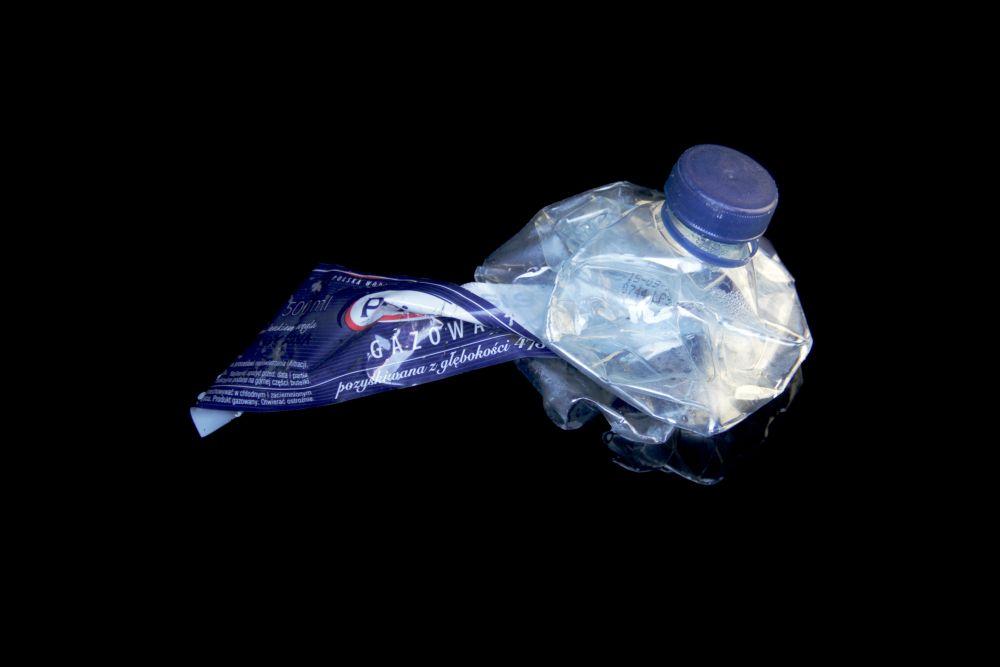 En hopknölad plastflaska mot en svart bakgrund.