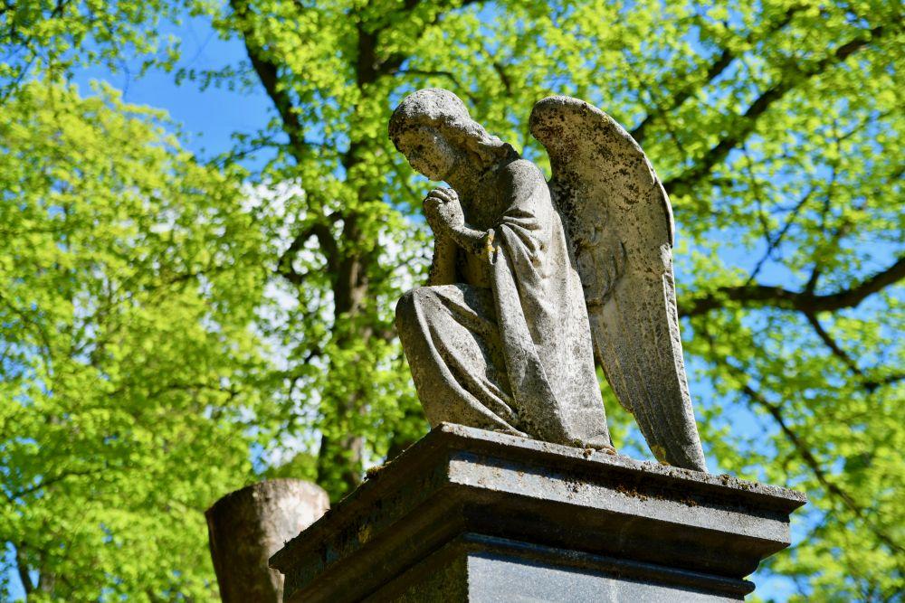 Ängel av marmor på en piedestal på en gravgård.