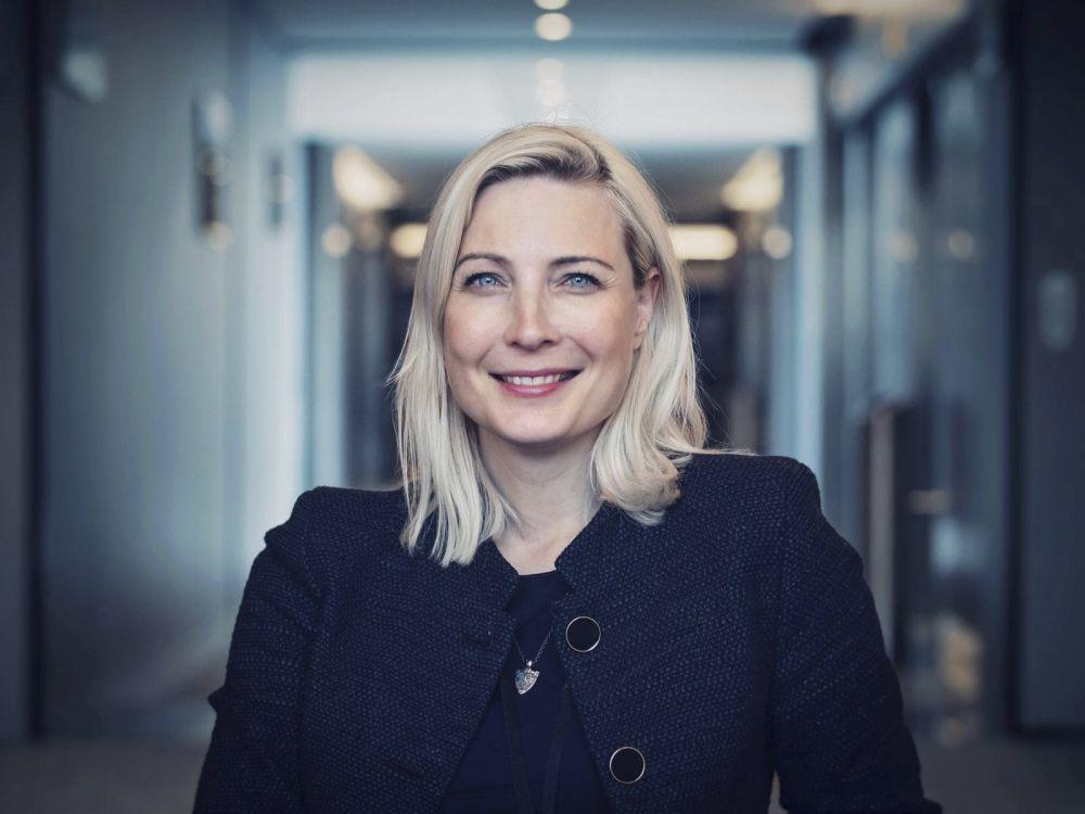Porträtt av en leende, blond, vit kvinna.
