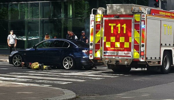 Brandman ligger vid bil i korsning