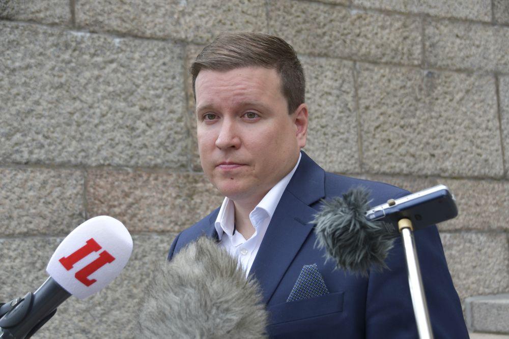 Kostymklädd man talar till media.