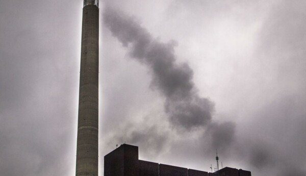 rykande industriskorsten mot molnig himmel