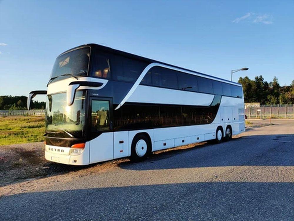 En vit buss i två våningar står parkerad vid vägrenen.