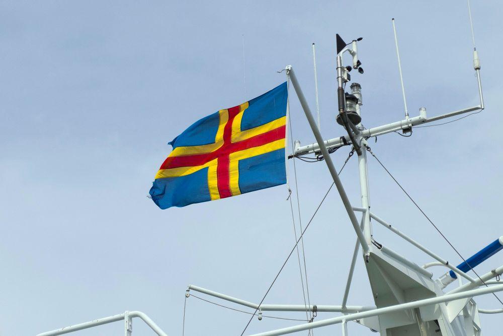 En blå himmel och Ålands flagga upphissad i en båt.