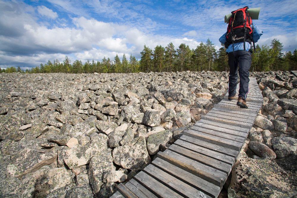 vandrare går på en broförsedd gång bland massor av stenar