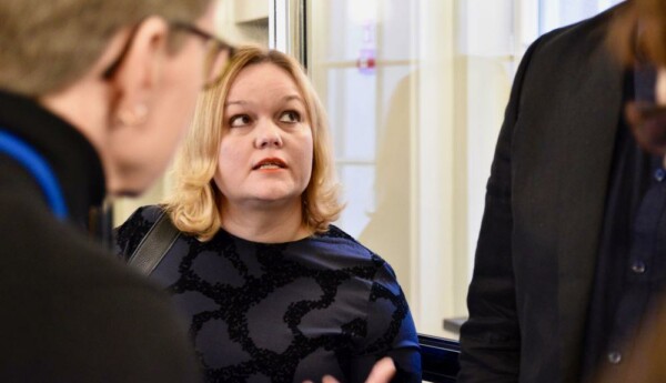 Blond kvinna pratar med ett par människor.