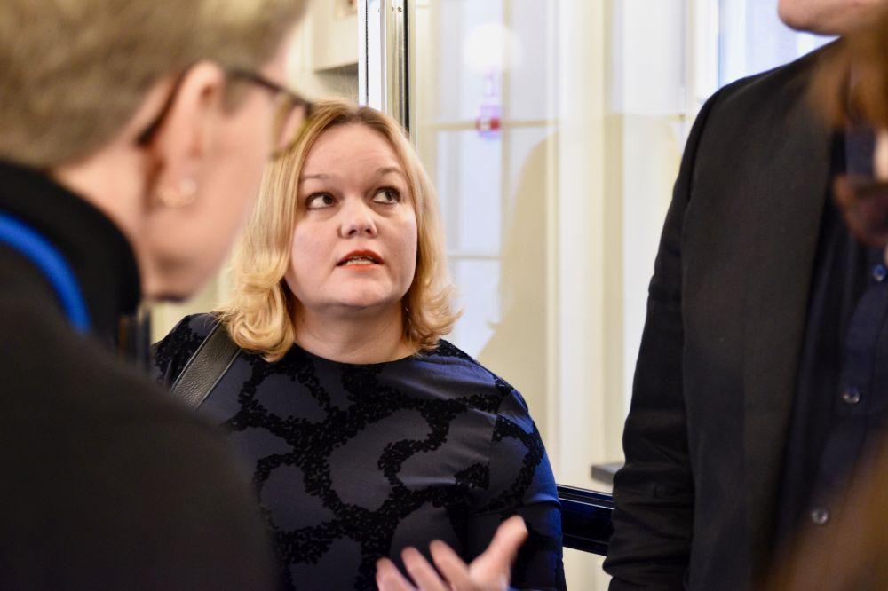 Blond kvinna pratar med ett par människor.