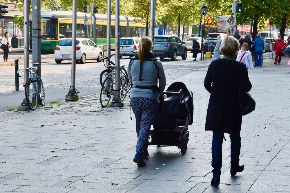 Männsikor på en gata, en kvinna med en barnvagn.