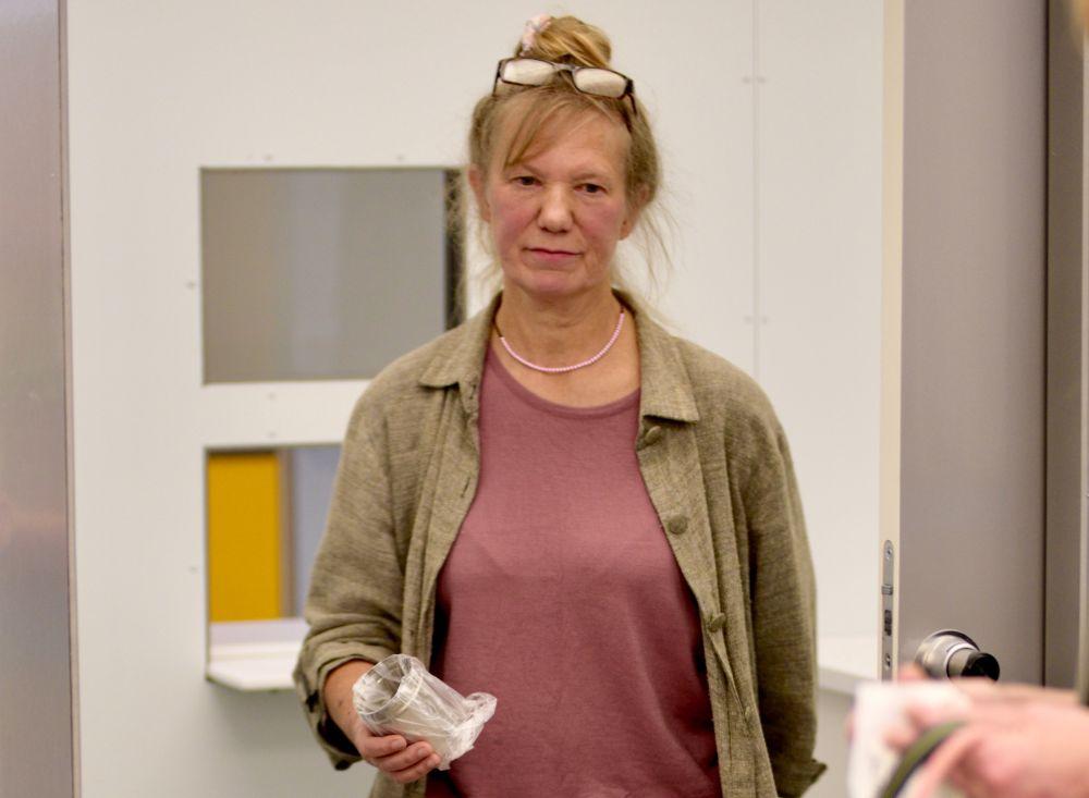 Kvinna med glasögonen på hjässan och en provburk i handen.