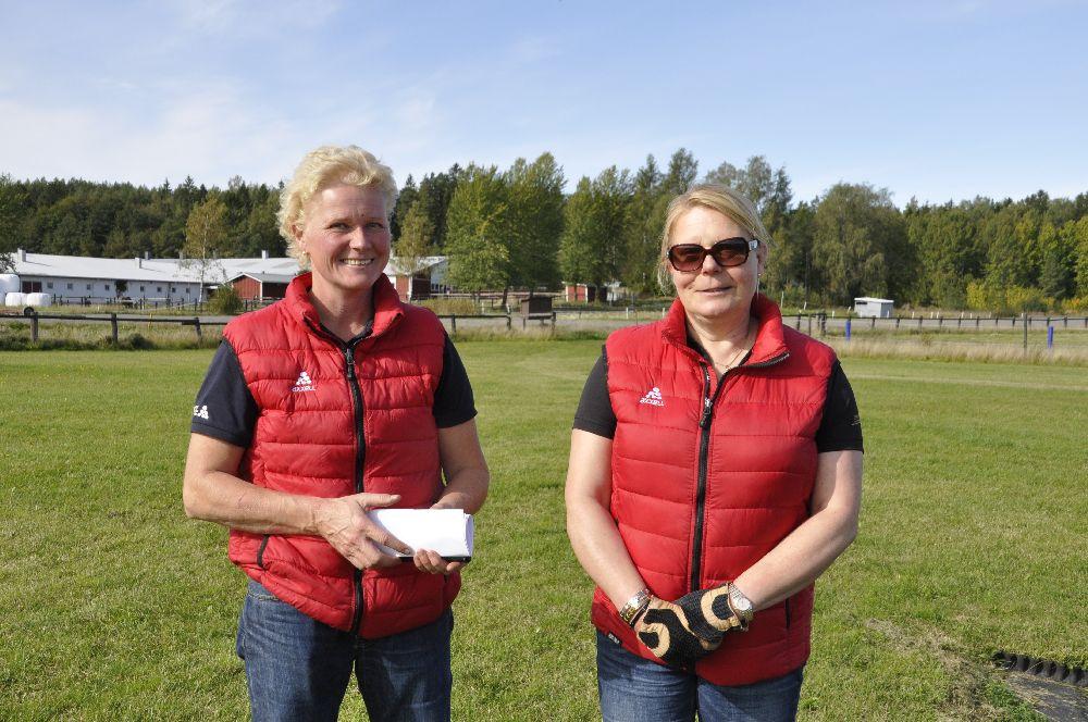 Två damer i röd väst på en stor gräsplan
