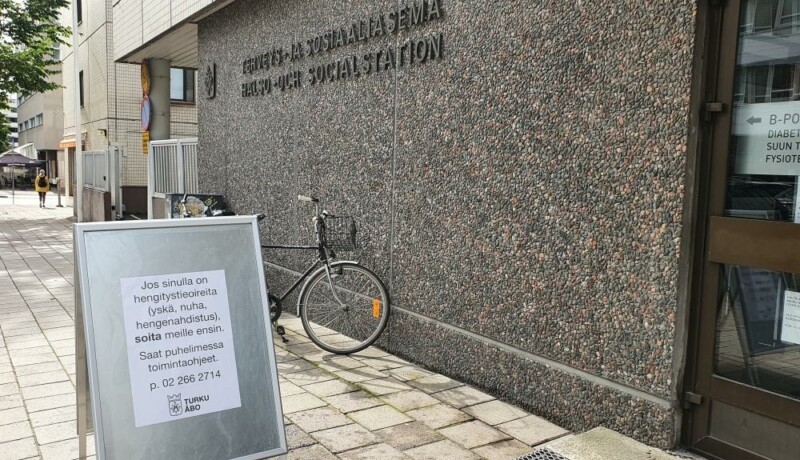 byggnad i Åbo, skylt utanför huset berättar att om du misstänker corona ska du ringa först, inte bara gå in