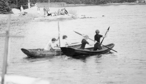 Svartvitt fotografi på barn i roddbåtar.