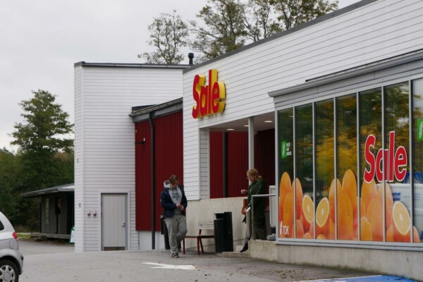 två personer möts vid ingången till en matbutik