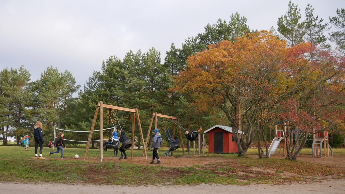 skolelever gungar och spelar boll på en skolgård i höstfärger