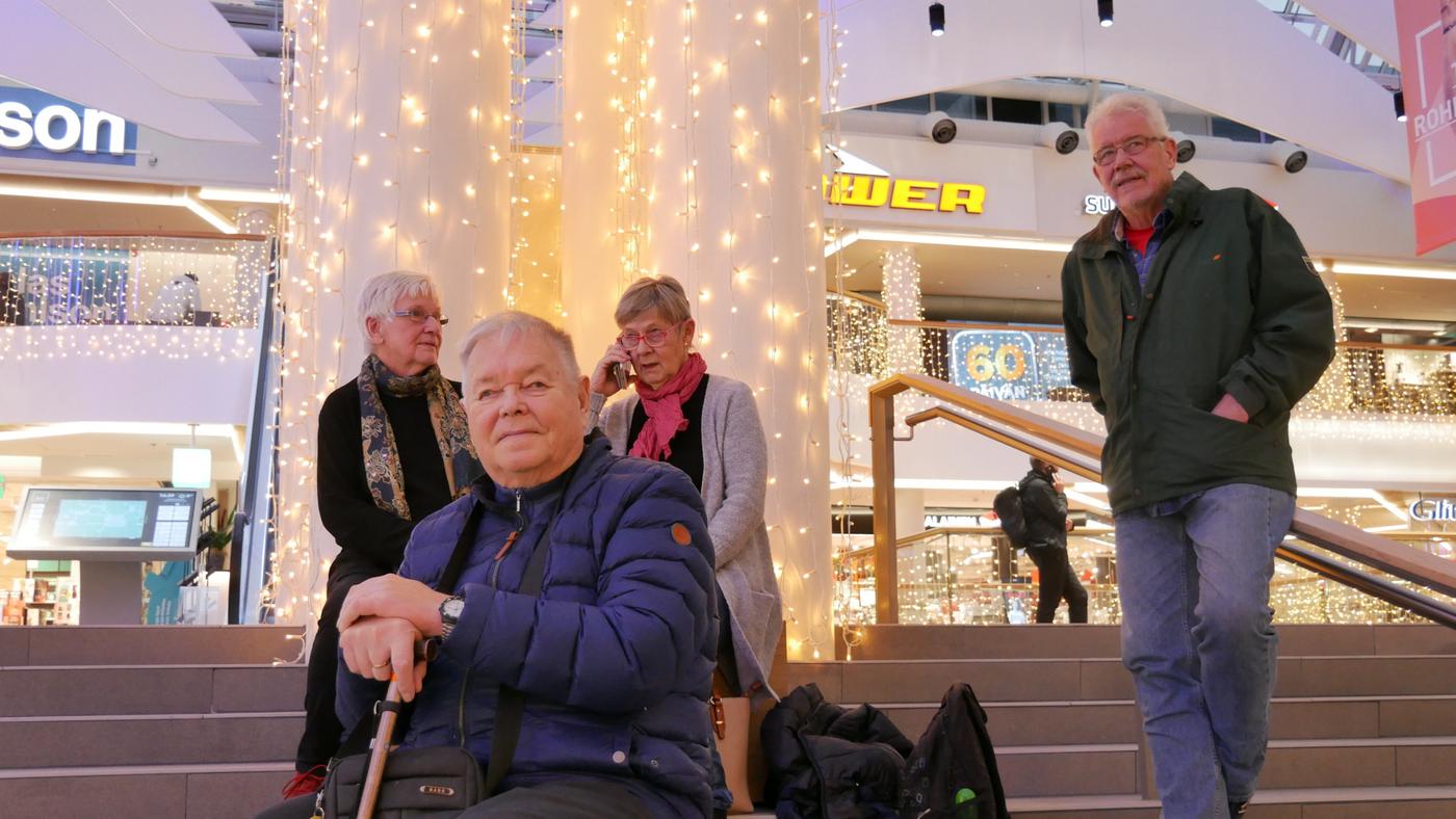 fyra äldre personer sitter tillsammans på en trappa inomhus