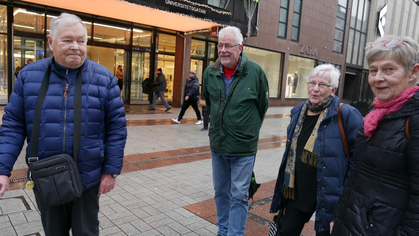 fyra äldre personer står i en klunga på gatan