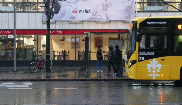 några personer står på en busshållplats och en buss kör in