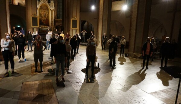 en kör värmer upp i en kyrka, med med avstånd från varann och munskydd på