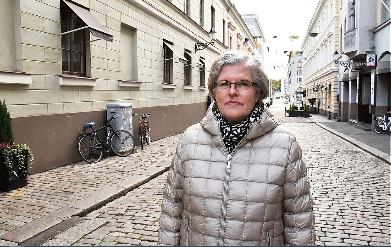 Katri Viinikka i grå jacka på en kullerstensgata i Helsingfors.