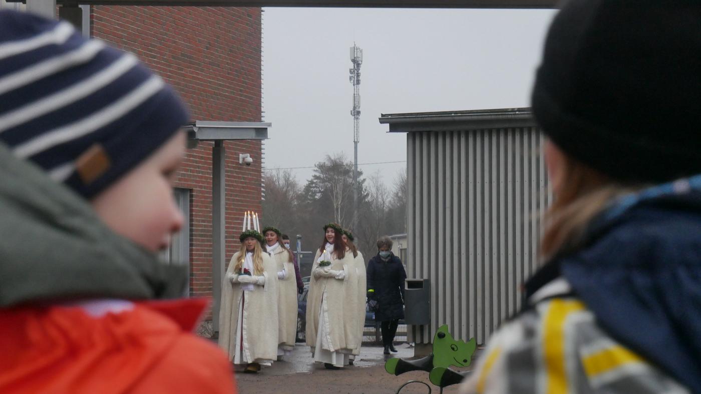 ett litet luciatåg i bakgrunden, i förgrunden två småbarn