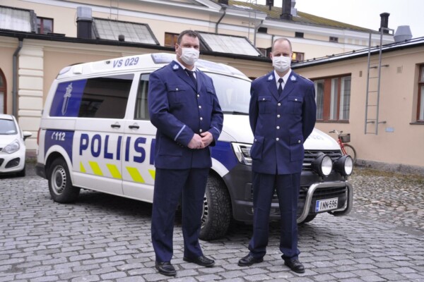 två poliser framför en bil