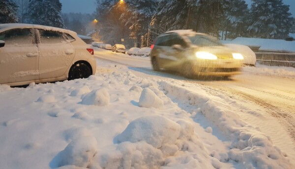 En bil som kör i snöyra med en snödriva i förgrunden.