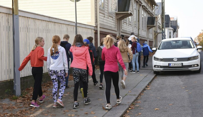 En grupp med barn går på trottoaren.
