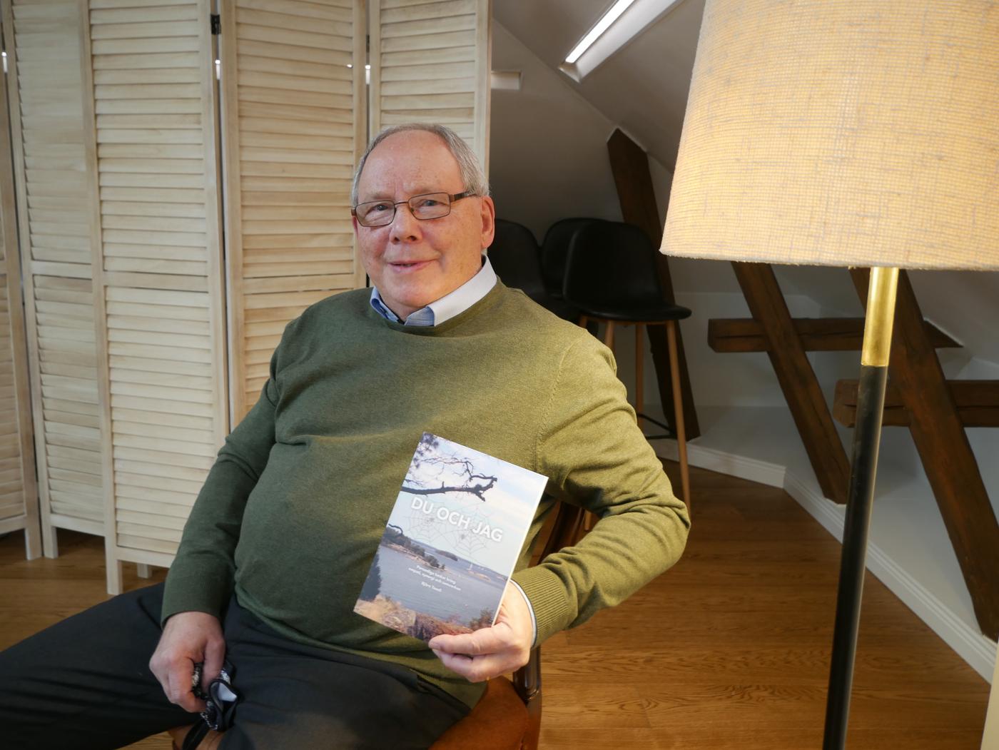 En äldre man håller upp en bok.