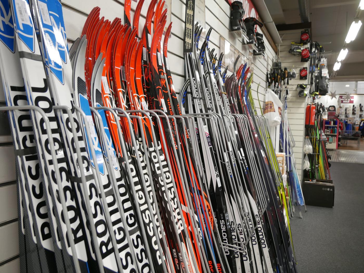 Skidor radade längs vägg i sportaffär.