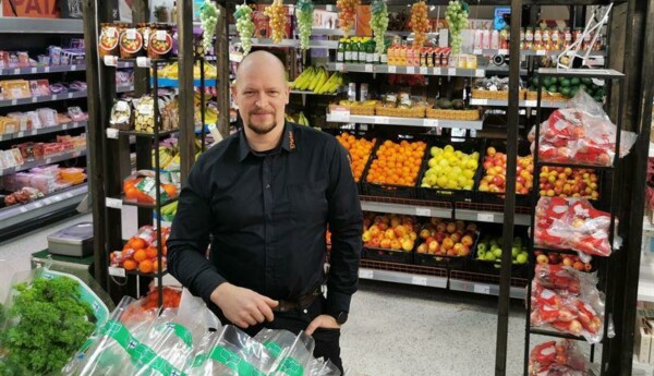 Man klädd i köpmanskläder bland butikshyllor