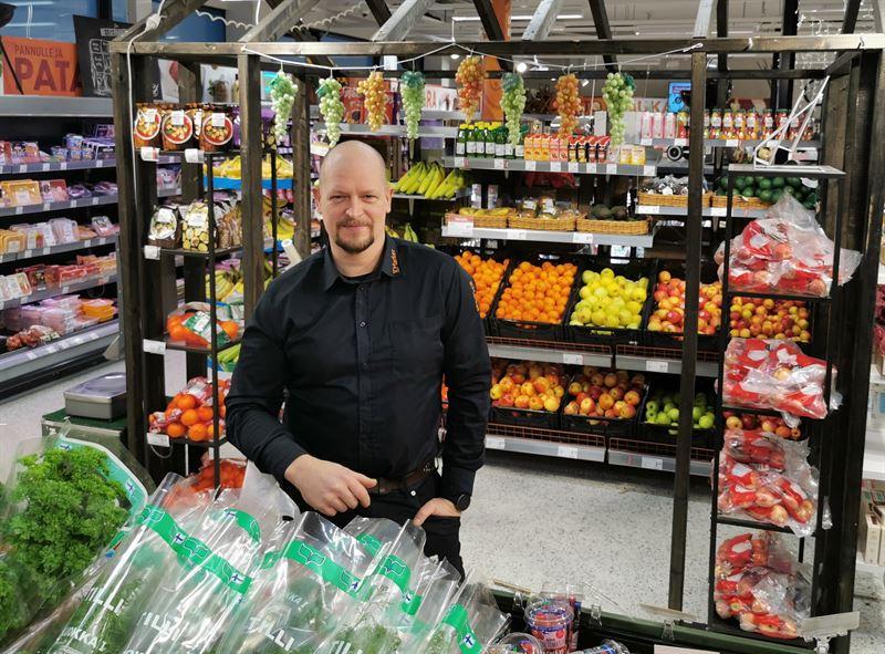 Man klädd i köpmanskläder bland butikshyllor