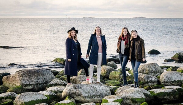 Fyra kvinnor står på strandstenar